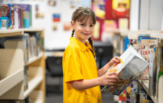 A photo of a St Thomas More’s Catholic Primary School Brighton-Le-Sands student reading in the library and on the way to 2025 NAPLAN results success